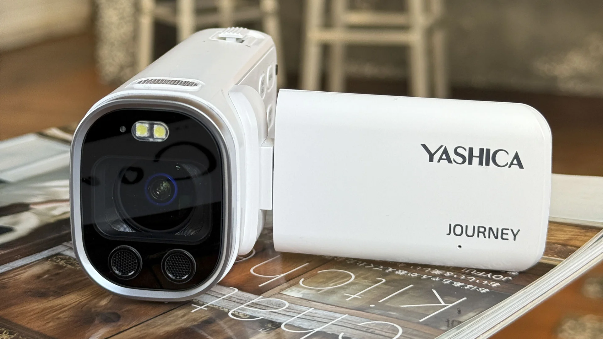 Yashica Journey 4K camcorder in white, rested on a surface with screen flipped out