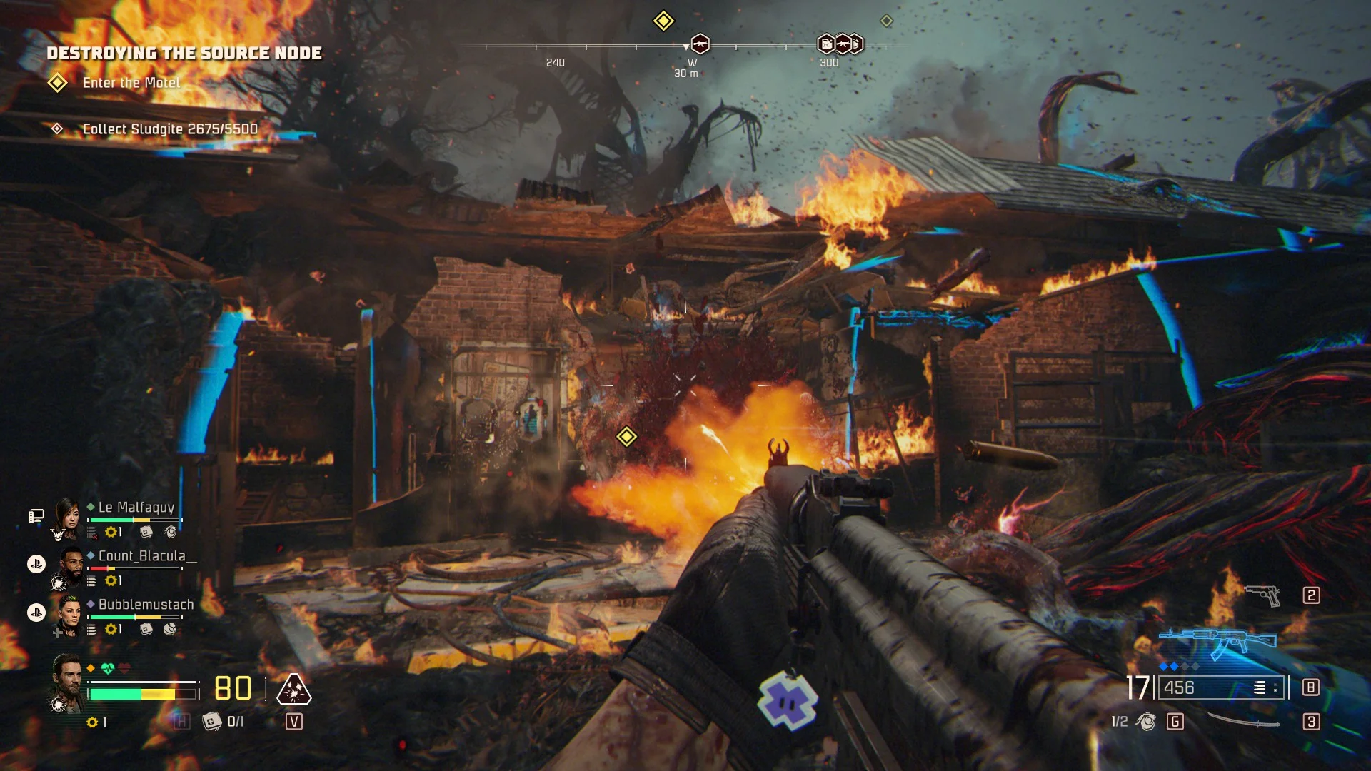 A John Carpenter's Toxic Commando screenshot that shows the player engaging a group of zombies with an AK style rifle in the ruins of a burning shed.