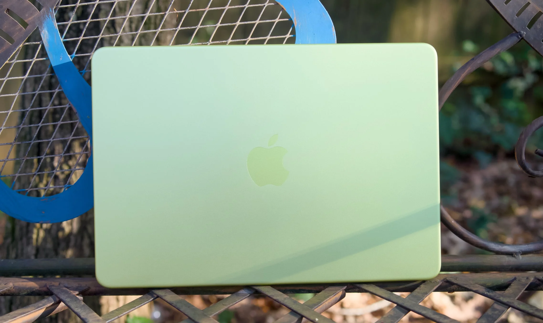 A citrus MacBook Neo on a table outside.